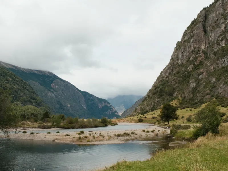 A braided Patagonian river winding through a green valley below rock cliffs