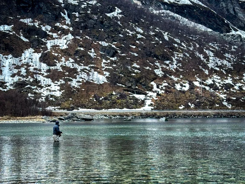 Wading the clear shallows under the mountain, snow still on the slopes
