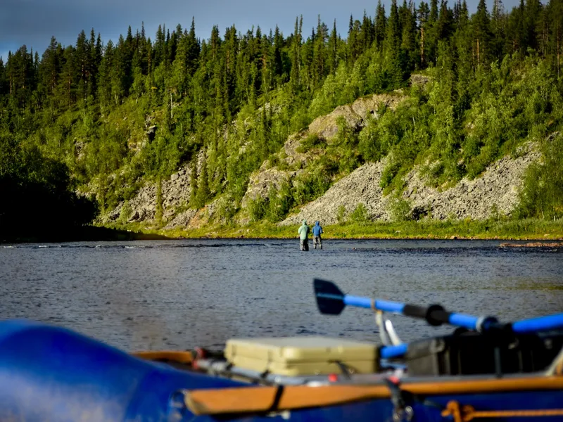 Camp on the bank: tipi, the raft and two anglers in the distance
