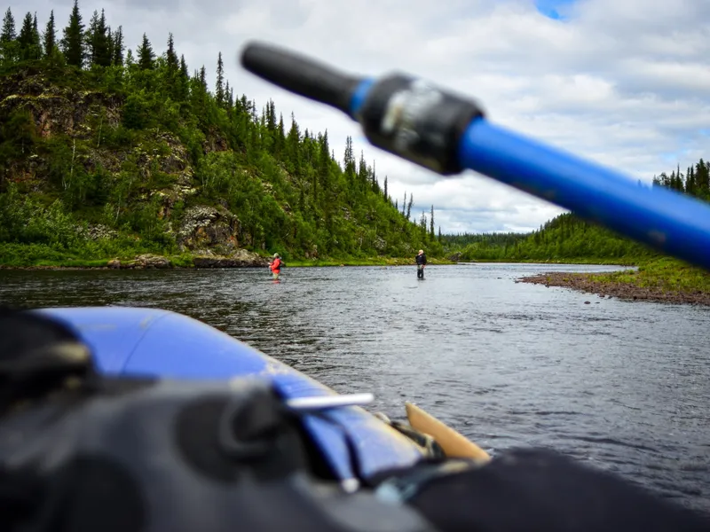 Two anglers wading a run, the raft pulled up below