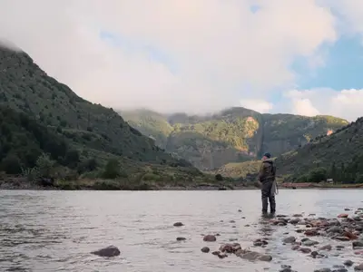 An angler wading the Río Mañihuales with the valley opening behind him